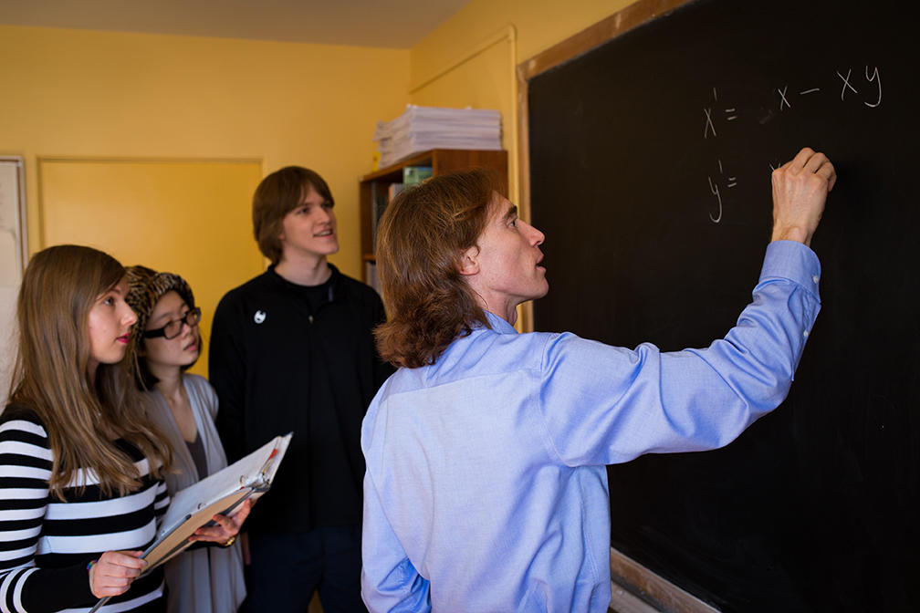 a professor writing on a blackboard