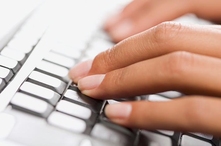Fingers typing on laptop keyboard.