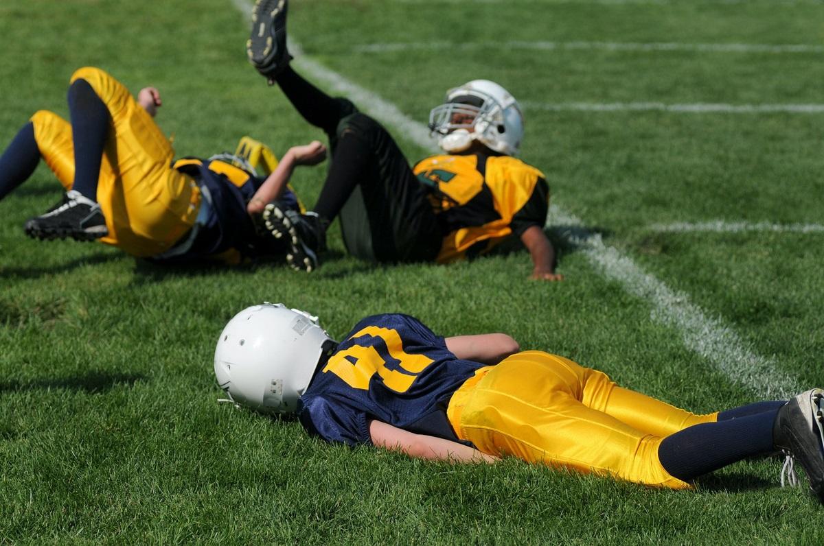 Child football game with one youngster knocked out on ground