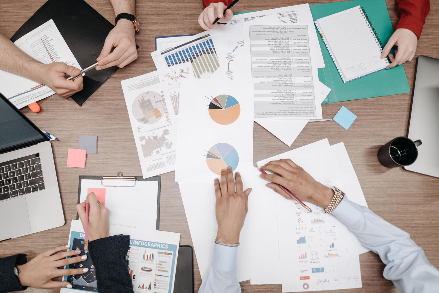 Piles of papers and charts on collaborative working table.
