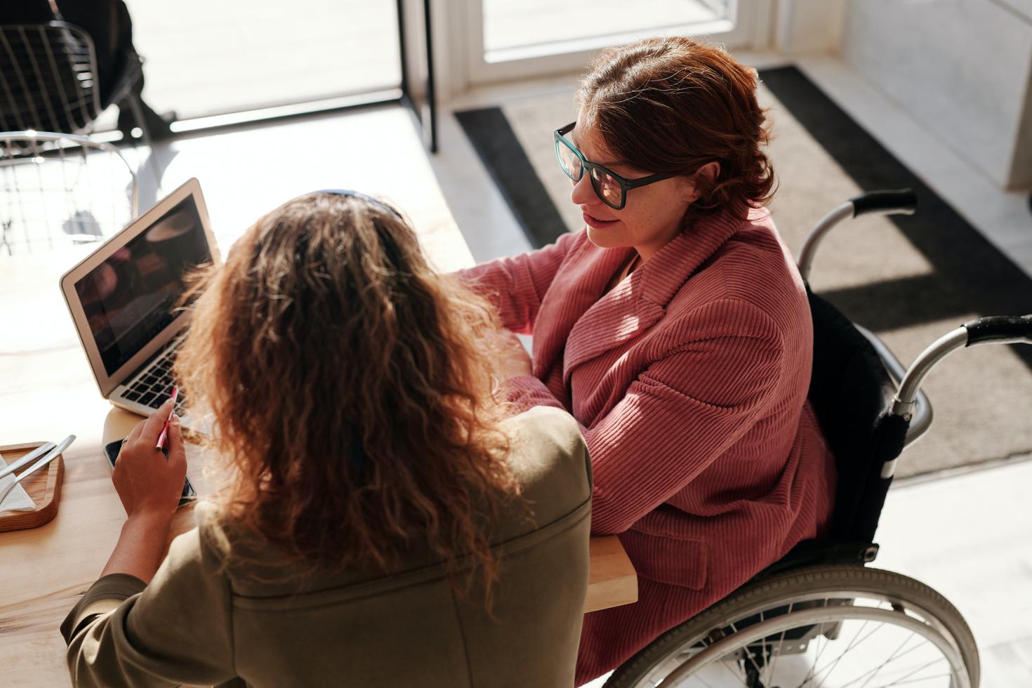 Woman sitting with woman in wheelchair 