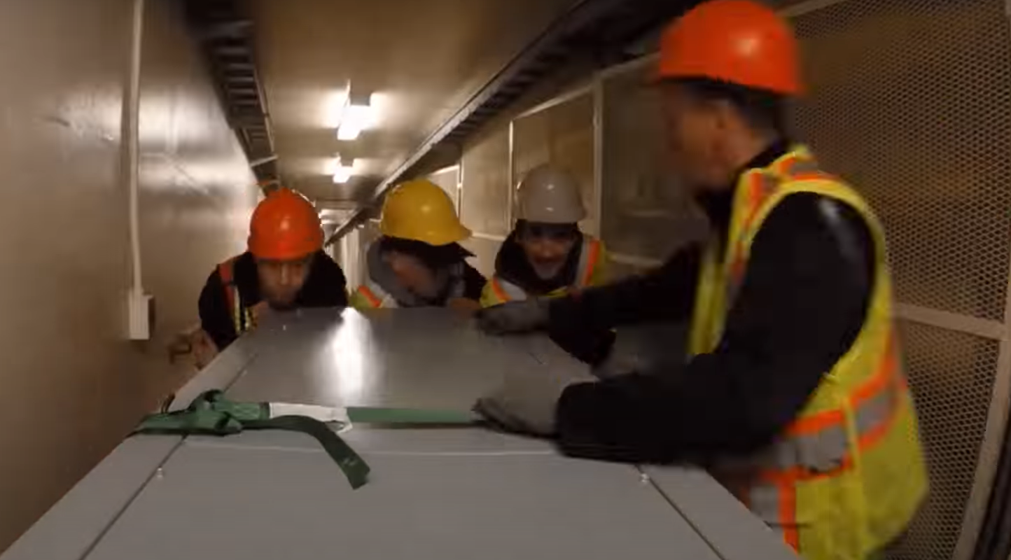 Three men lifting an equipment