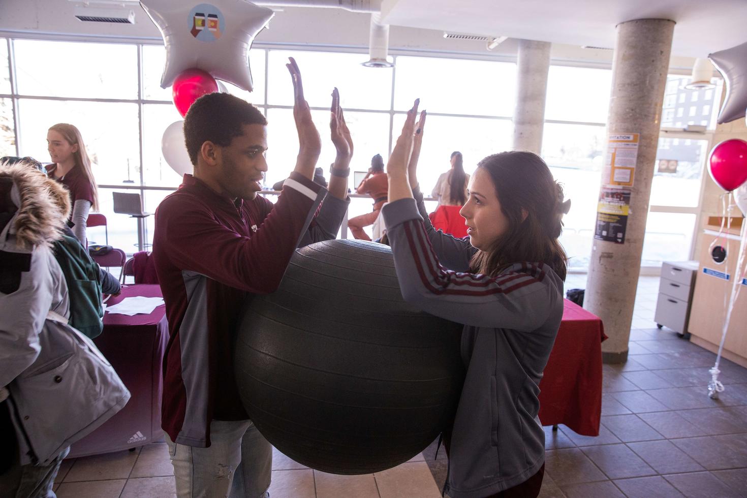 Two students holding a ball between them with no hands