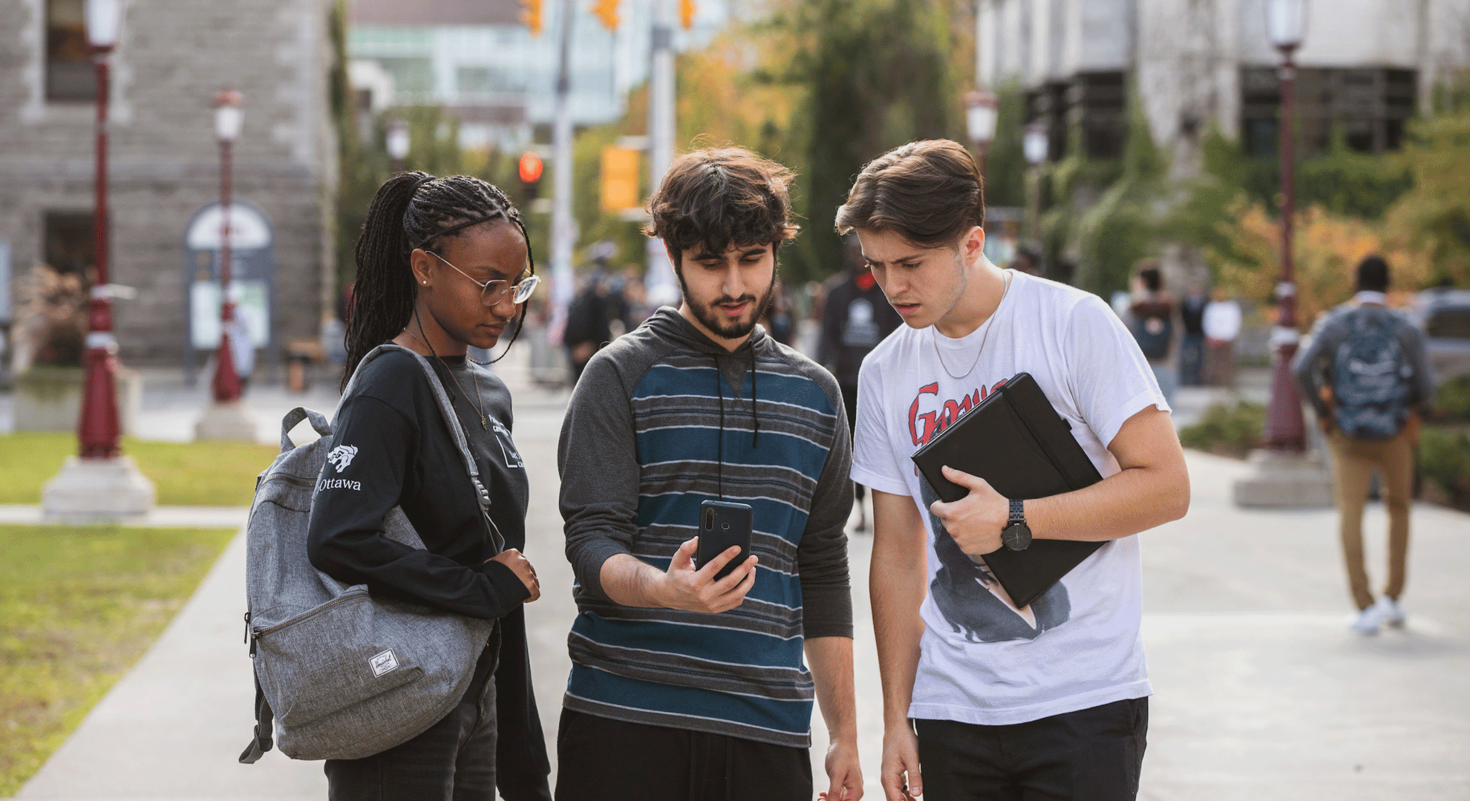three students looking at a mobile phone 