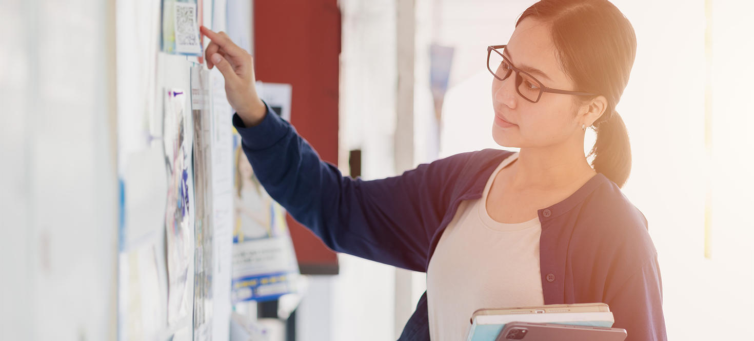 Woman posting posters on a billboard