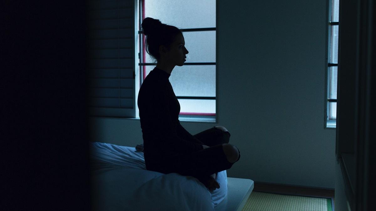 Woman sitting up on bed in dark