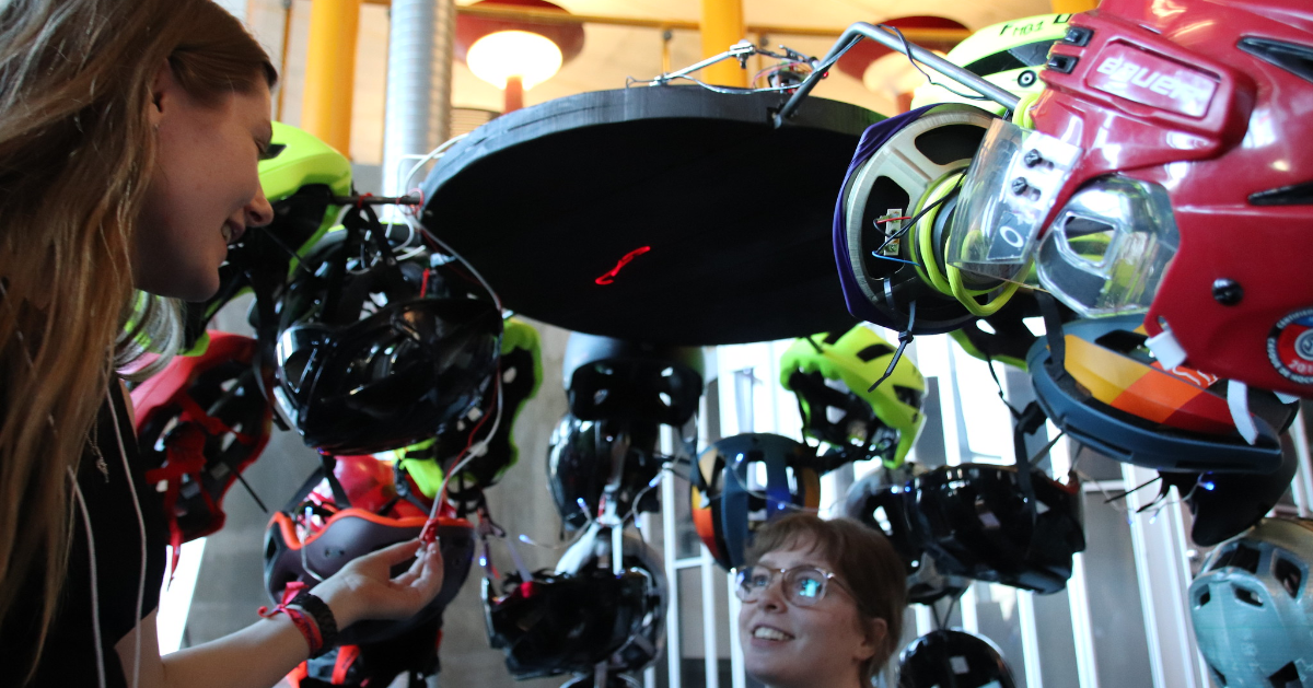 Two women talking with helmets over their heads