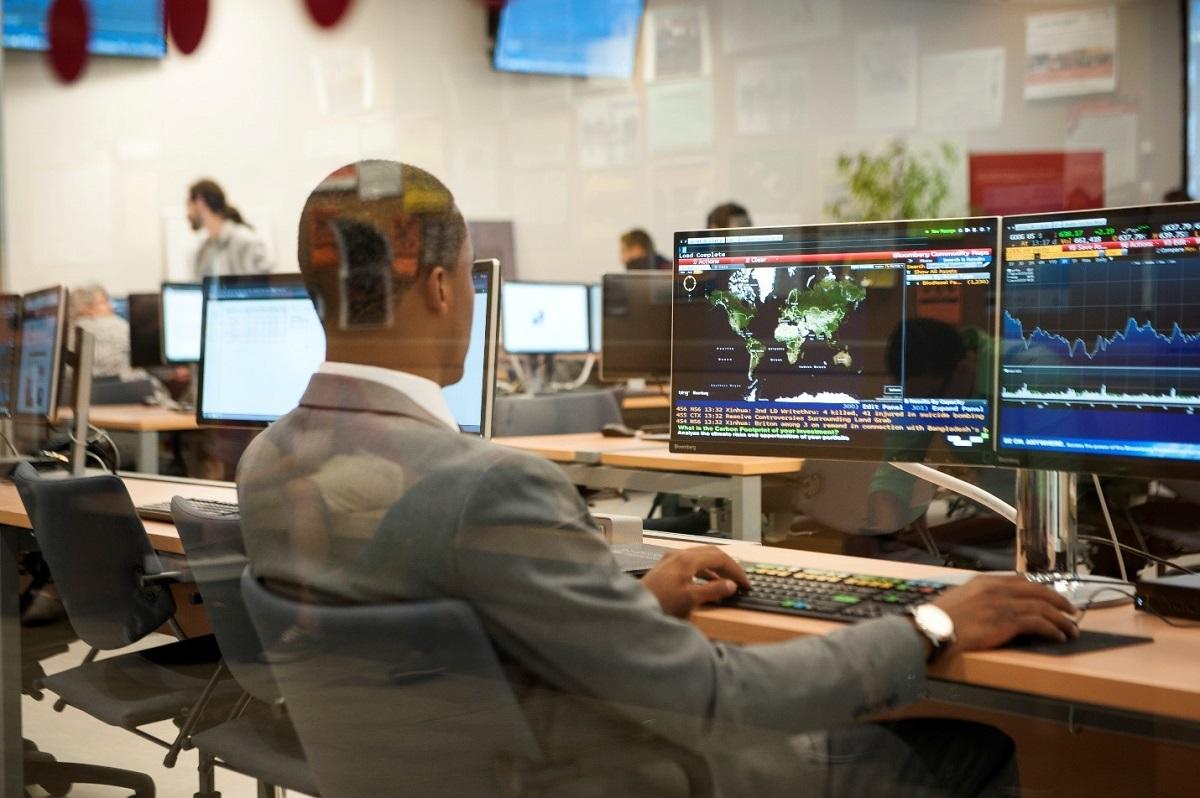 Rear profile of man in suit at desk using computer