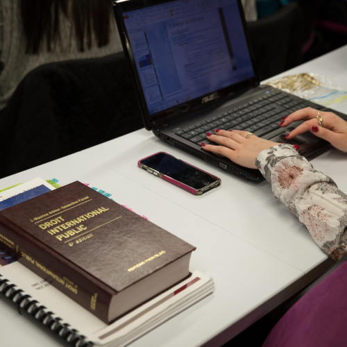 hands typing on laptop next to law book
