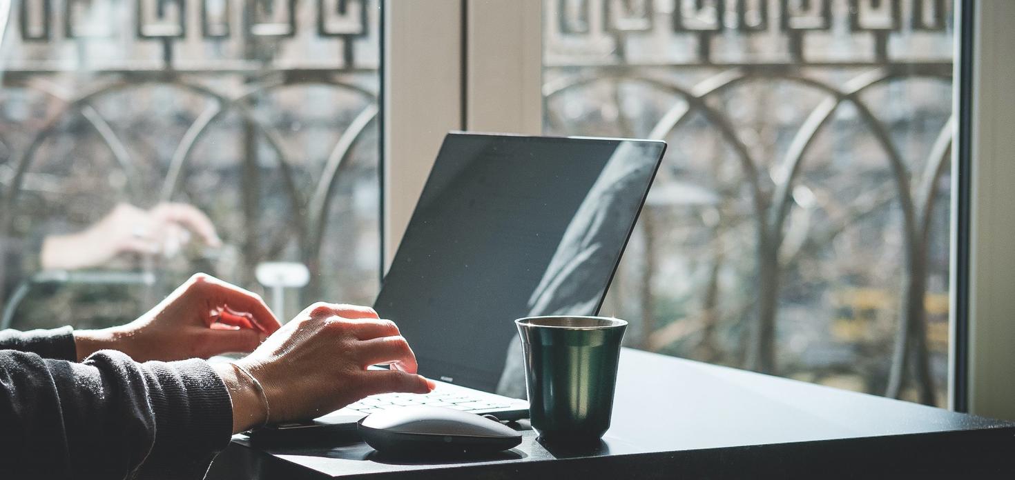 Personne à l'ordinateur avec une tasse de café.