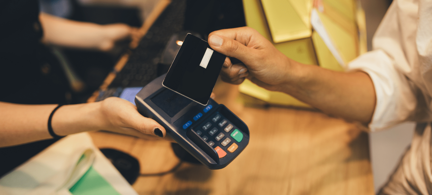 Une personne passe sa carte sur un terminal de paiement tenu par une autre personne.