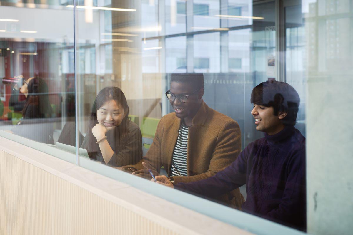 Students sitting by a window and working on a laptop