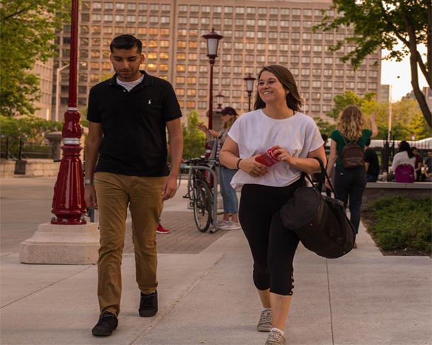 Homme et femme marchant à l'extérieur sur le campus de l'Université d'Ottawa