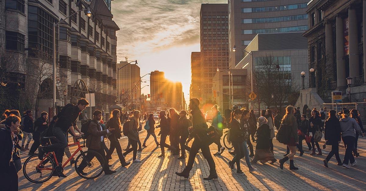 People walking on campus as sun sets behind them