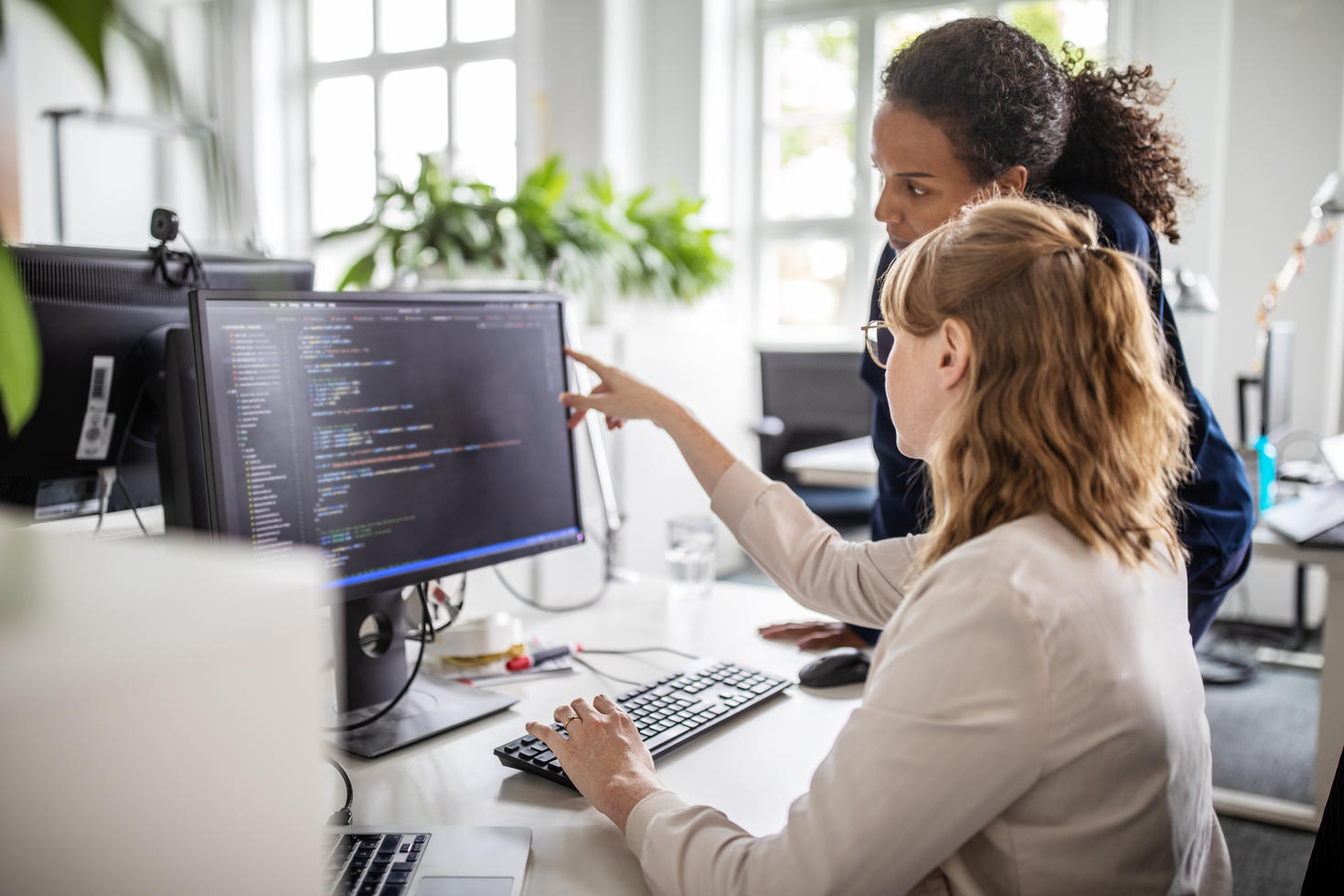 Employee pointing at computer screen to colleague.