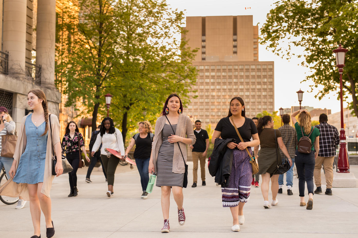Two Indigenous students walking ahead of a crowd on campus.