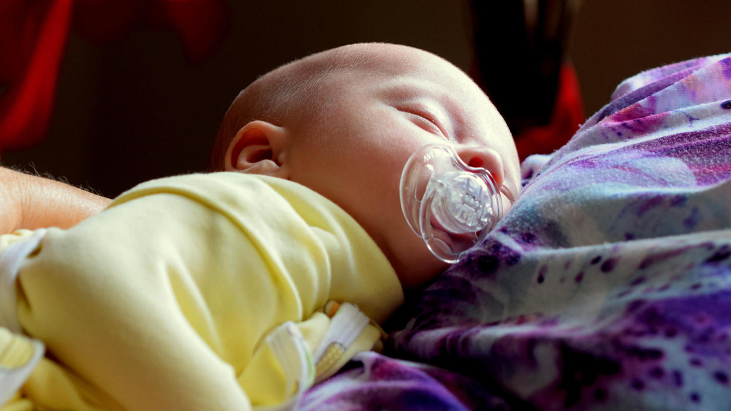 adorable baby sleeping held in adult's arms