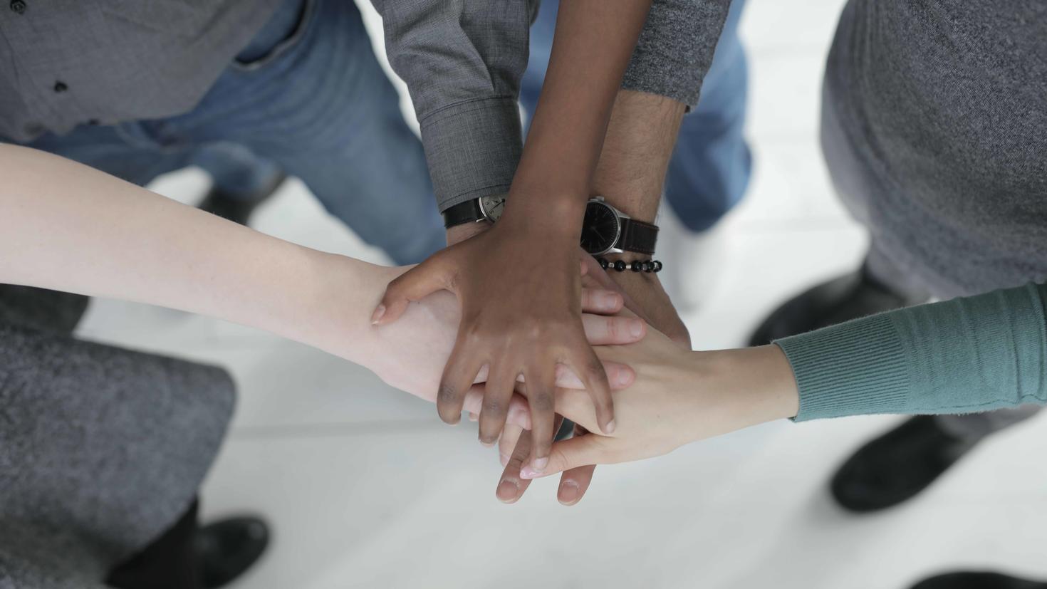 Unrecognizable colleagues joining hands