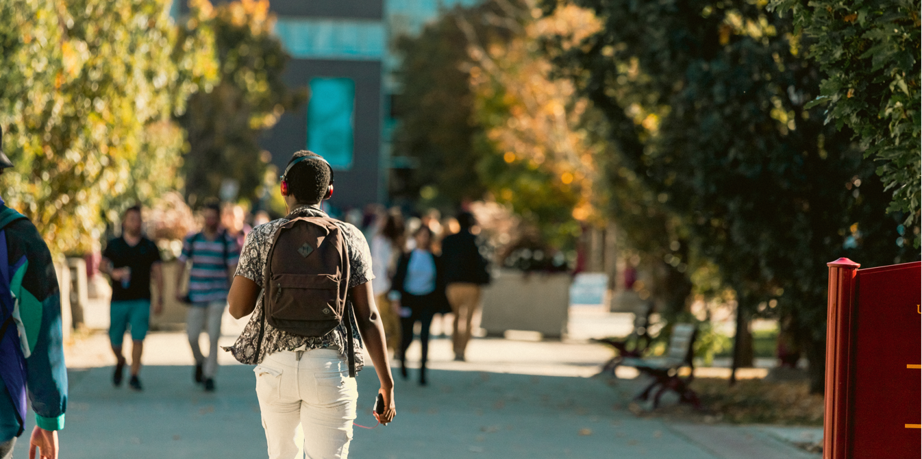 Student walking through campus with headphones on.
