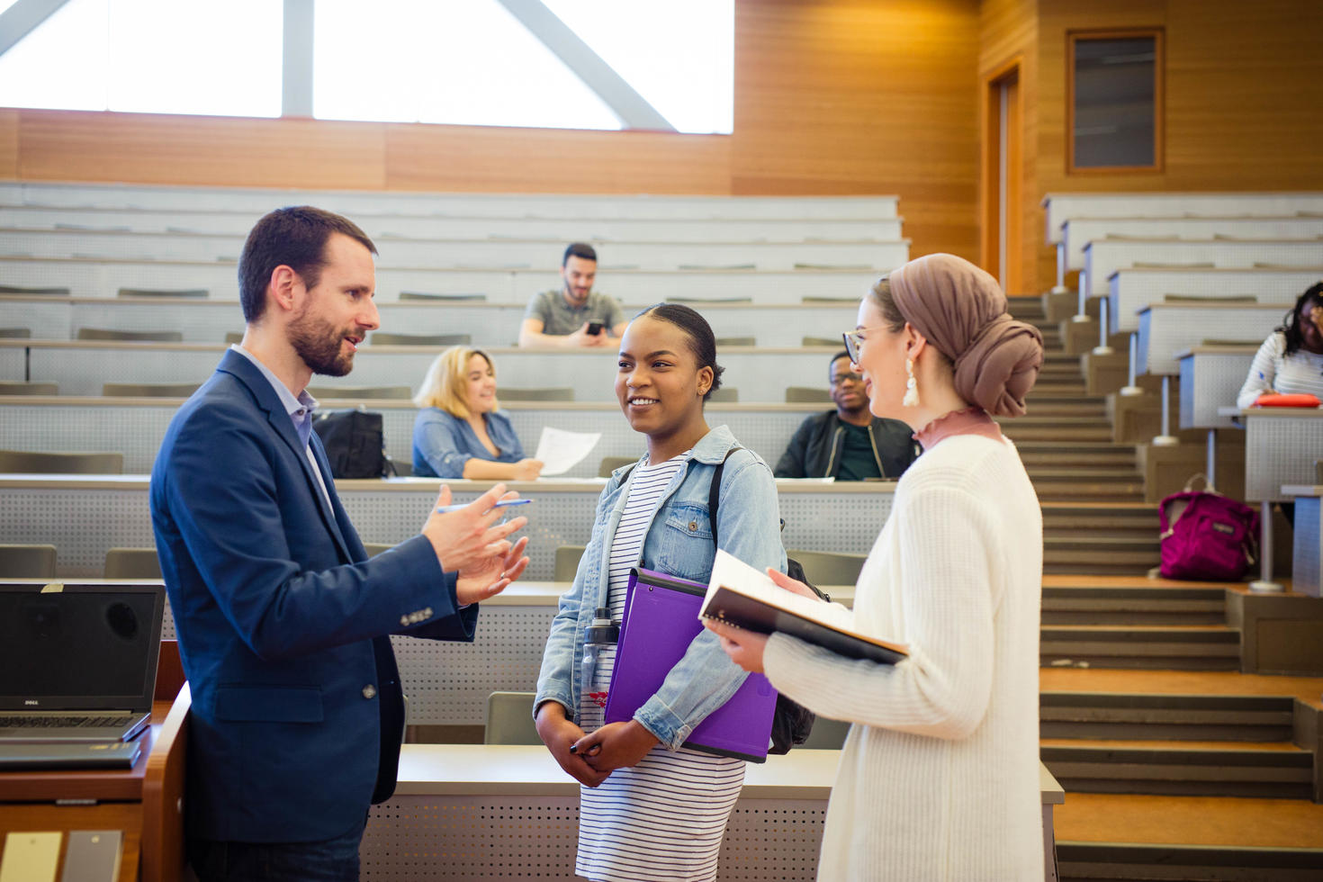 a professor talking to students after a classroom