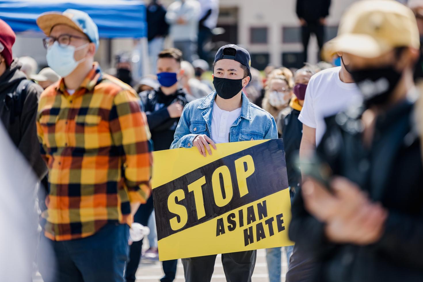 people wearing masks at a protest, person holding sign that says "Stop asian hate"