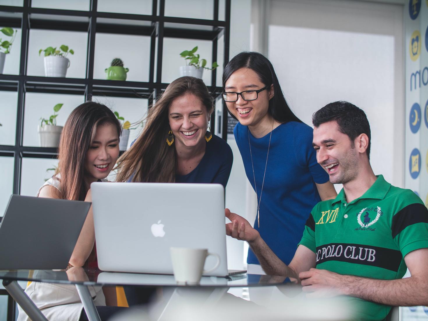 Four students practicing language skills around laptop