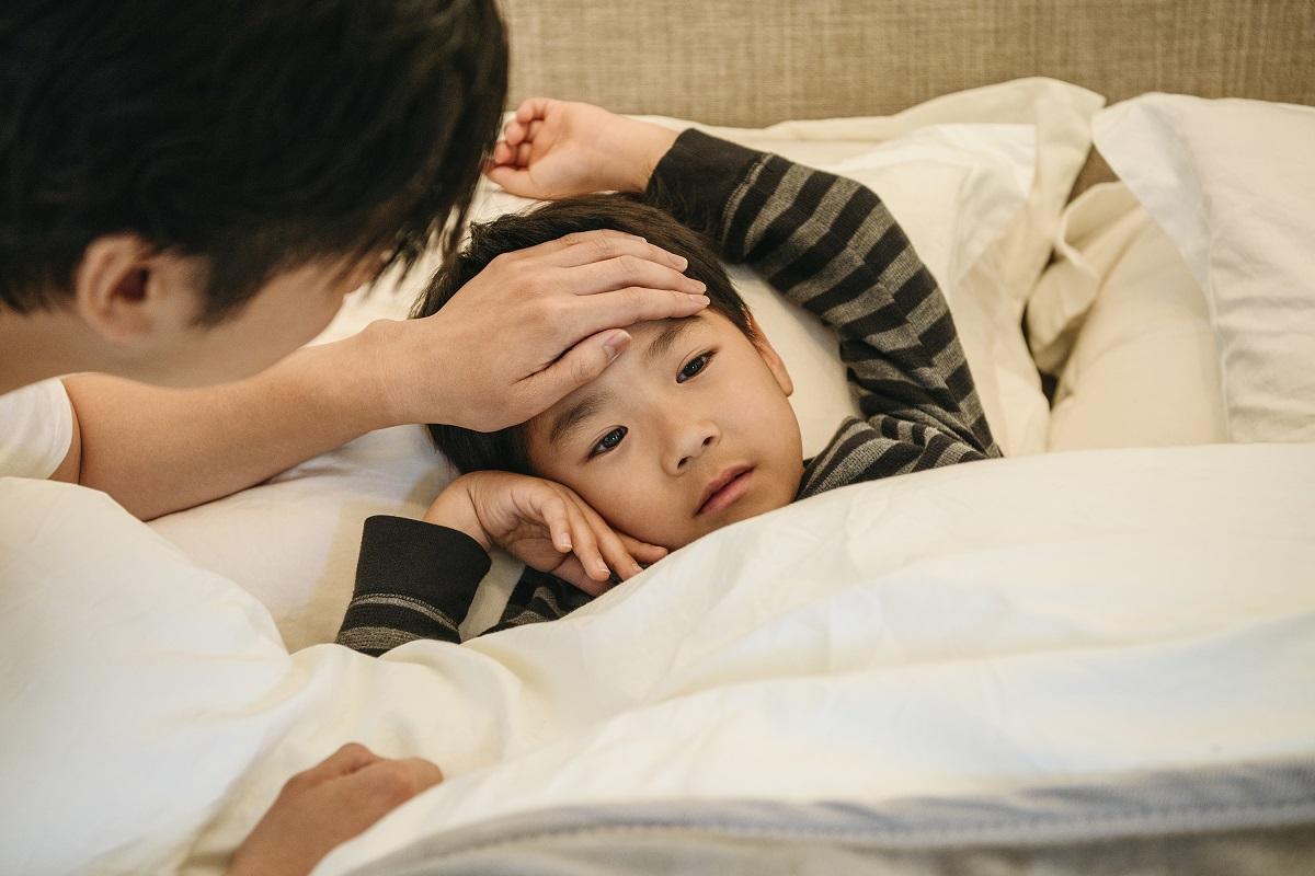 Young Asian boy sick in bed