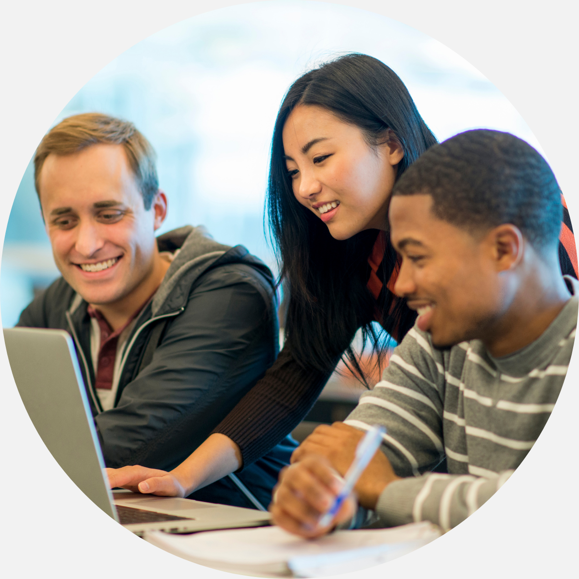 Three students in front of a laptop smiling