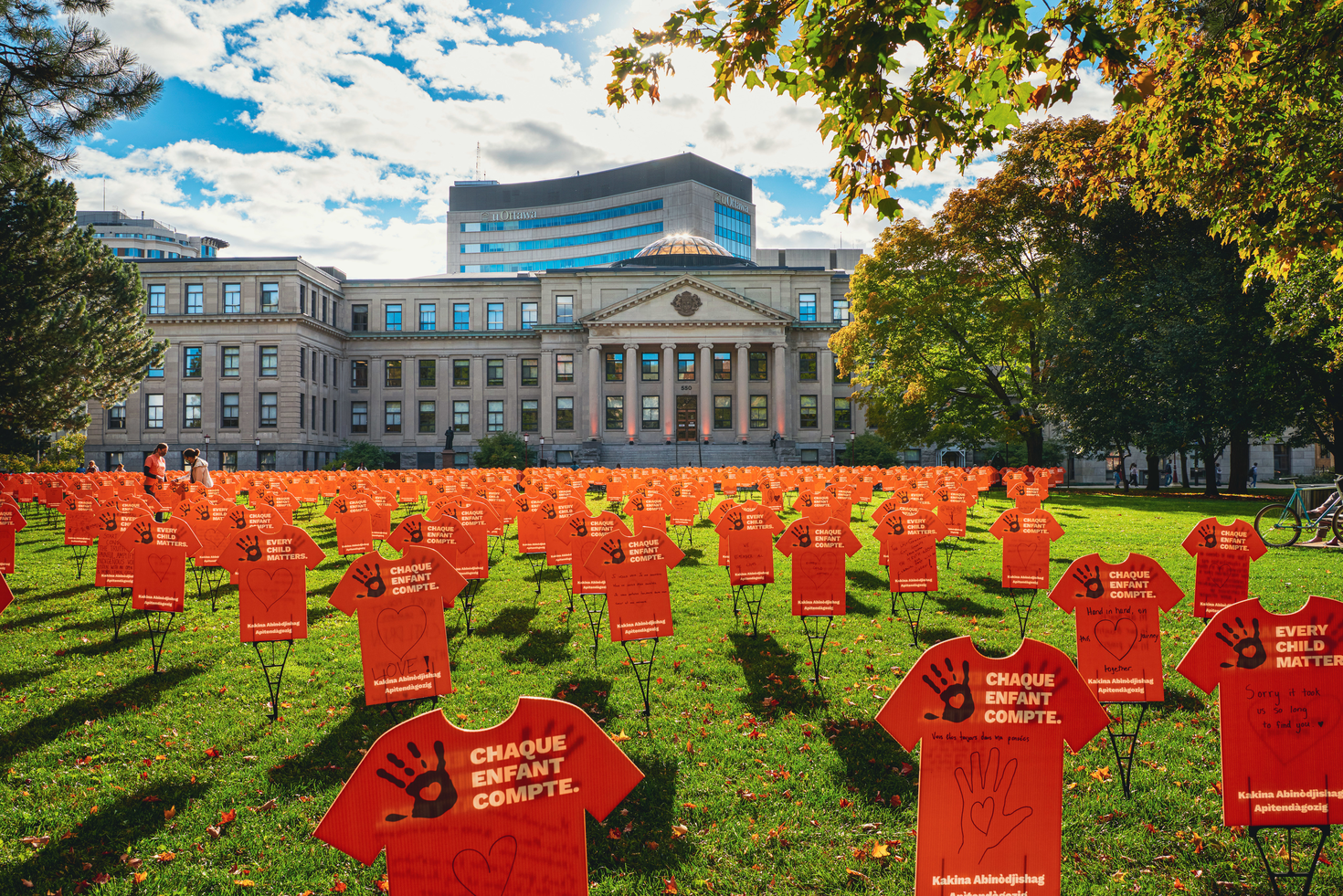 Orange shirts spread out across lawn in front of Tabaret Hall