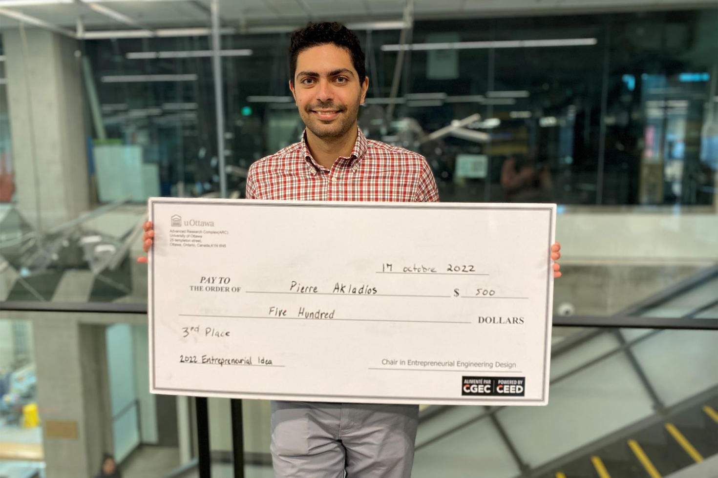 Engineering student Pierre Akladios holds a $500 check.