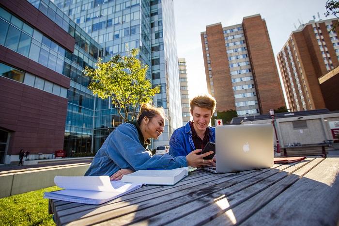 Students working on a table outside of the Faculty of Social Sciences building.
