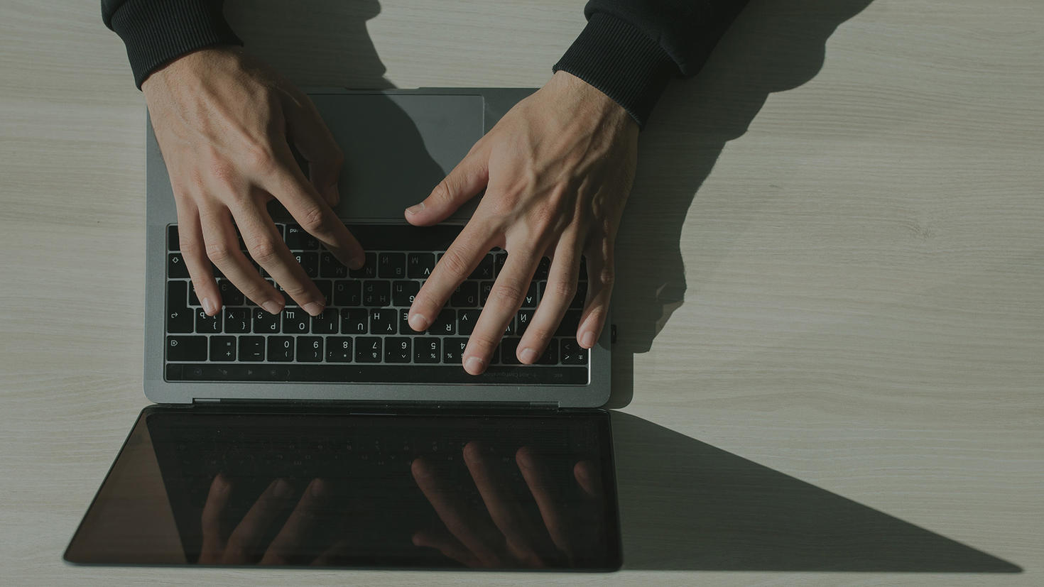 Hands working on a laptop.