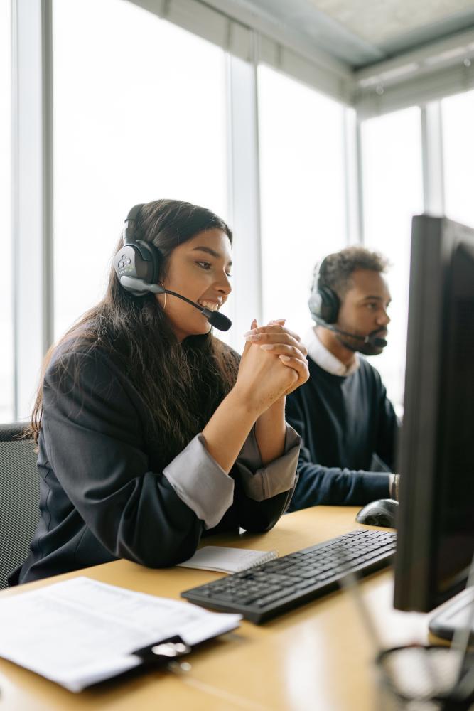 Employees with headsets working at a desktop