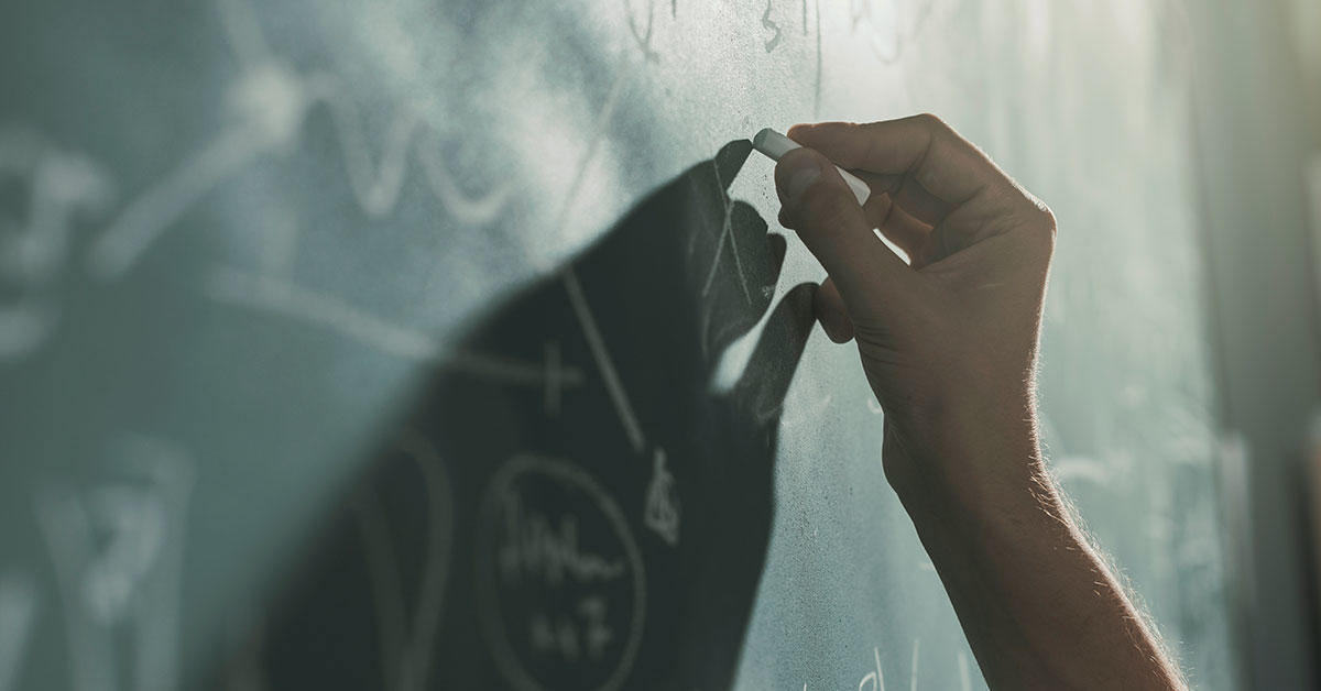 Someone writing on a blackboard.