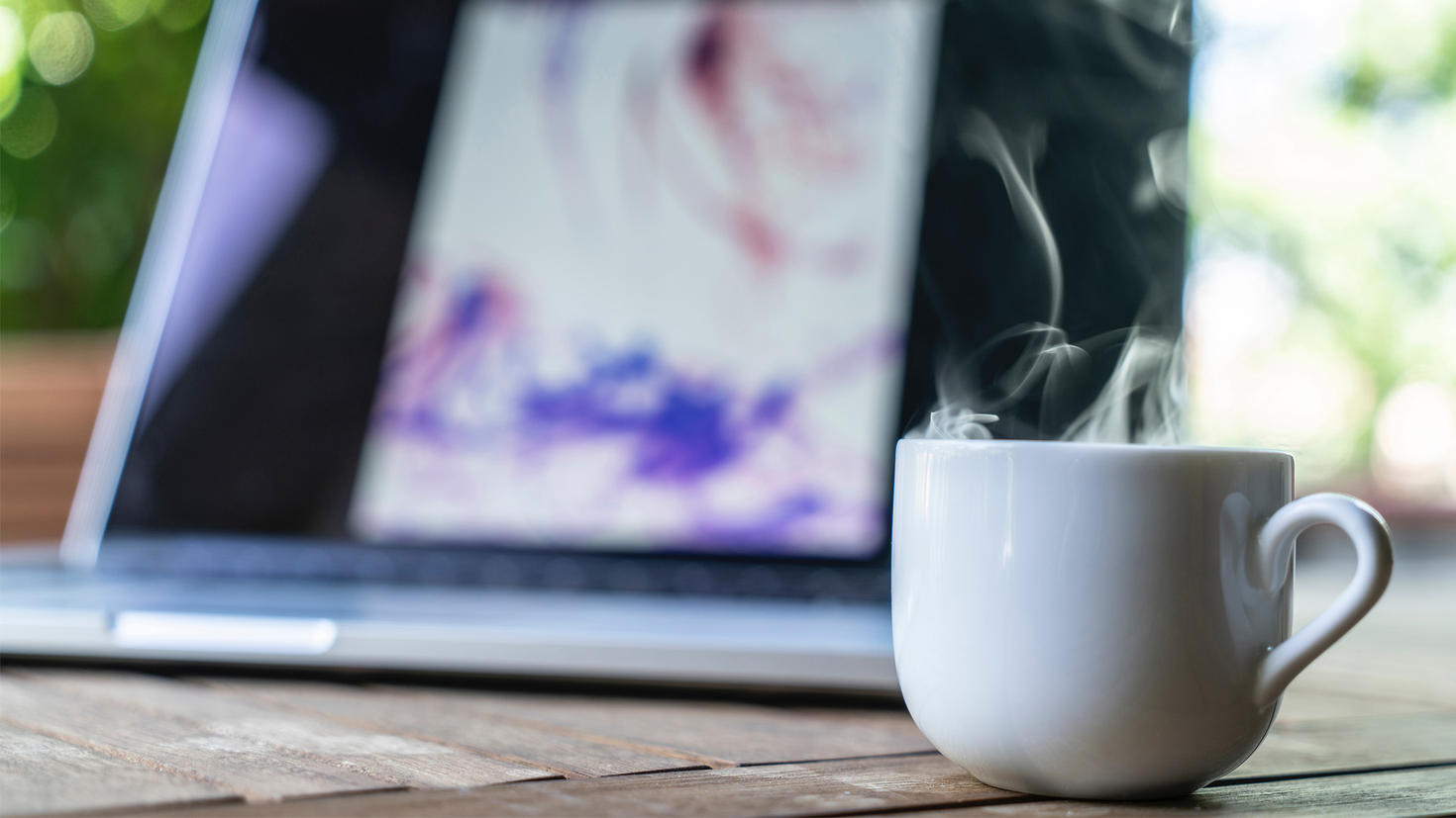 A cup of coffee next to a computer.