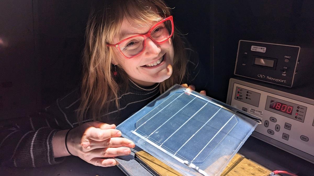 Erin Tonita holding a solar panel in a lab