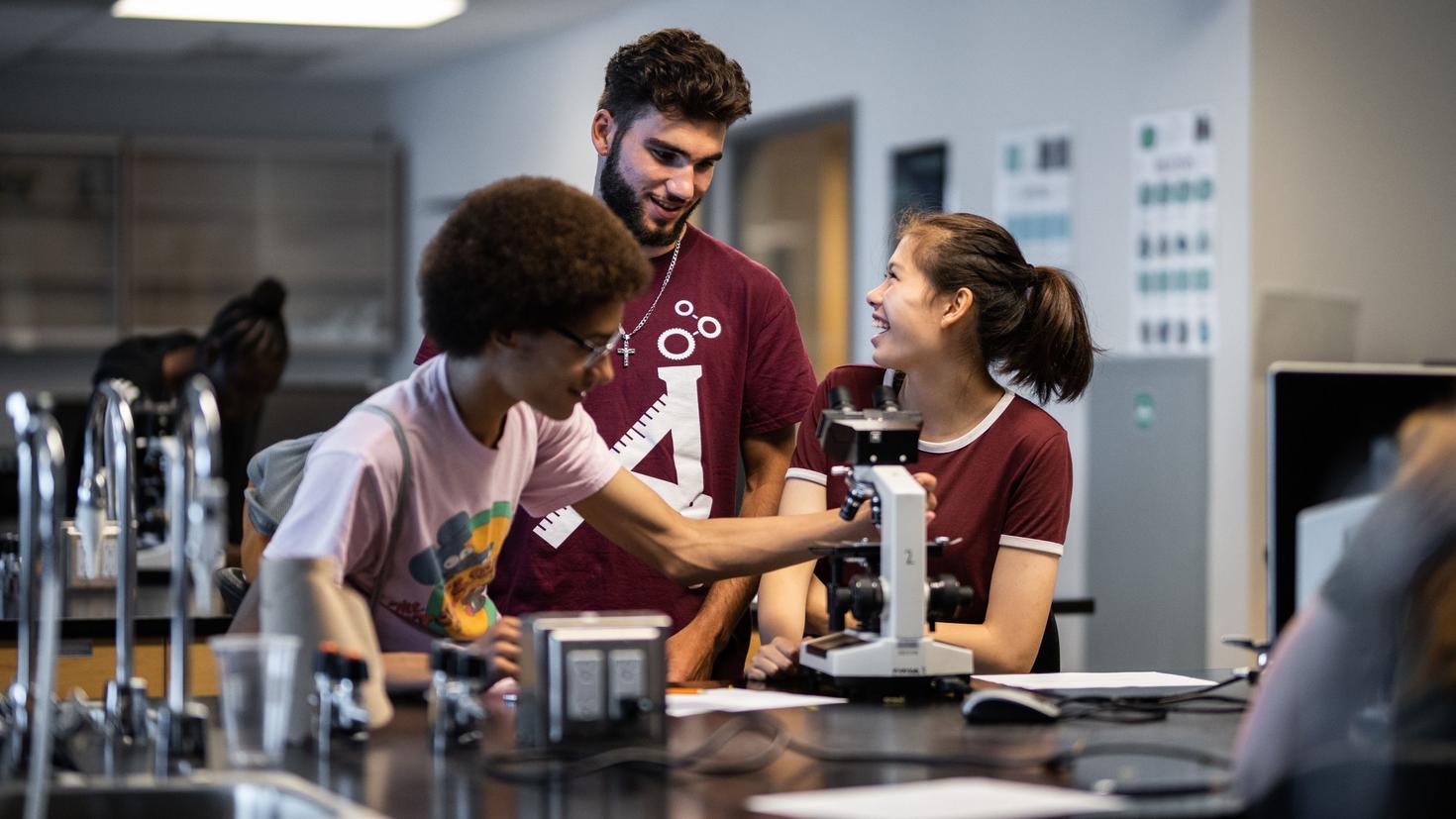 An instructor with teenage students in a lab.