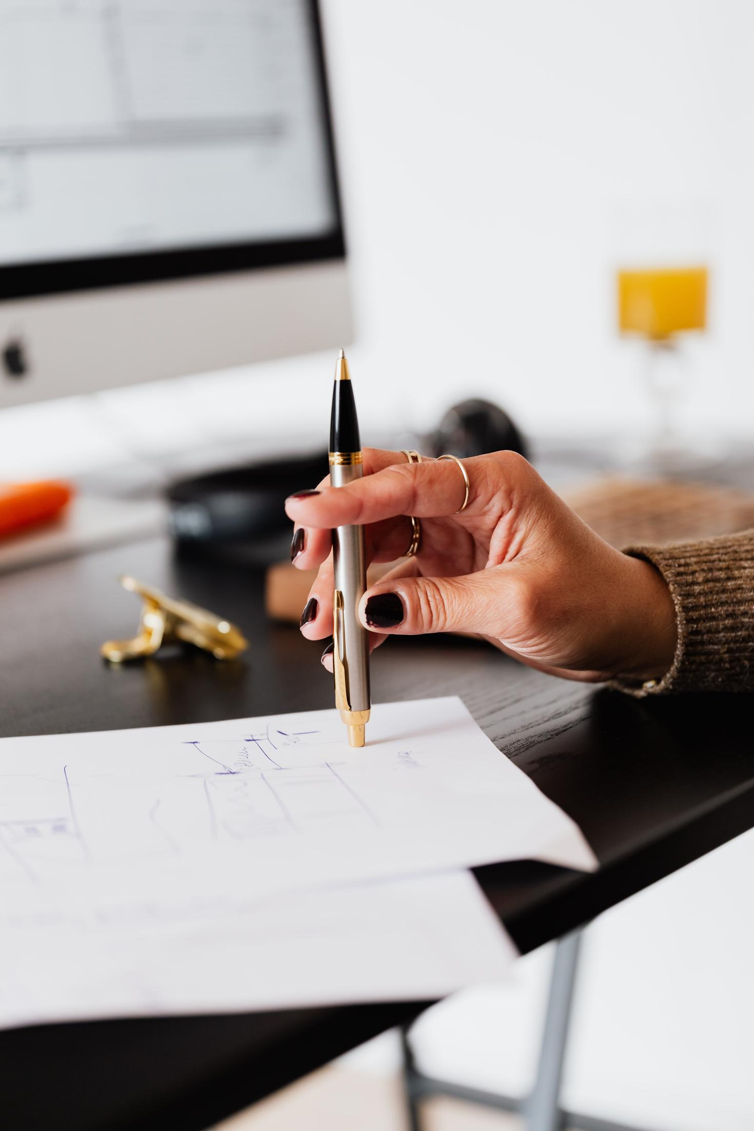 Woman hand holding pen taping paper on desk