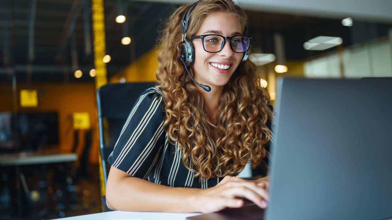 Woman wearing headsets and working on a laptop