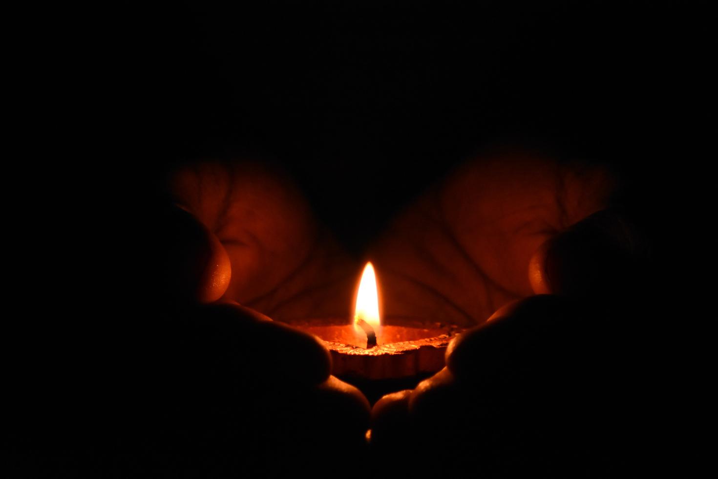 Two hands holding up a candle