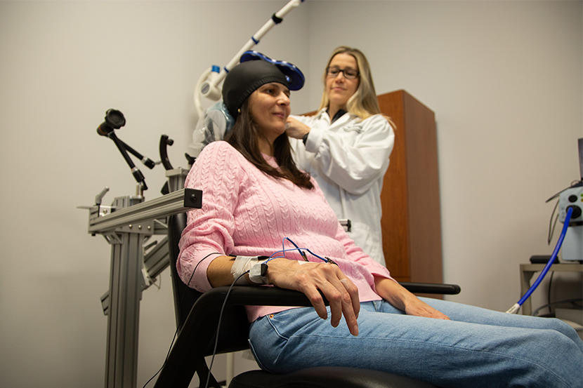 Research scientist Flavia Ignacio Antonio and visiting doctoral student Tatiana de Bem Fretta demonstrate a treatment protocol using repetitive transcranial magnetic stimulation.