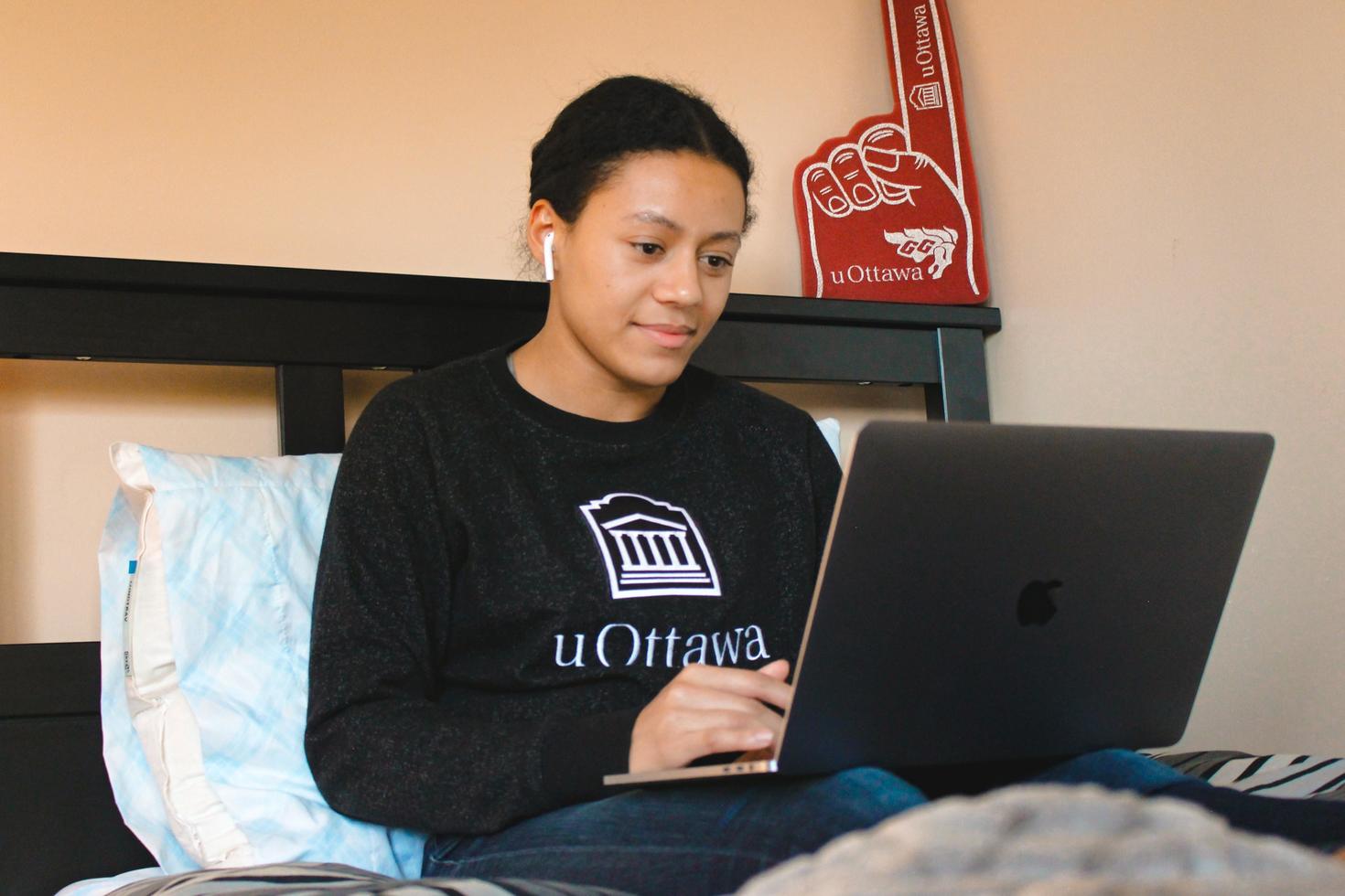 Student on their bed with their laptop