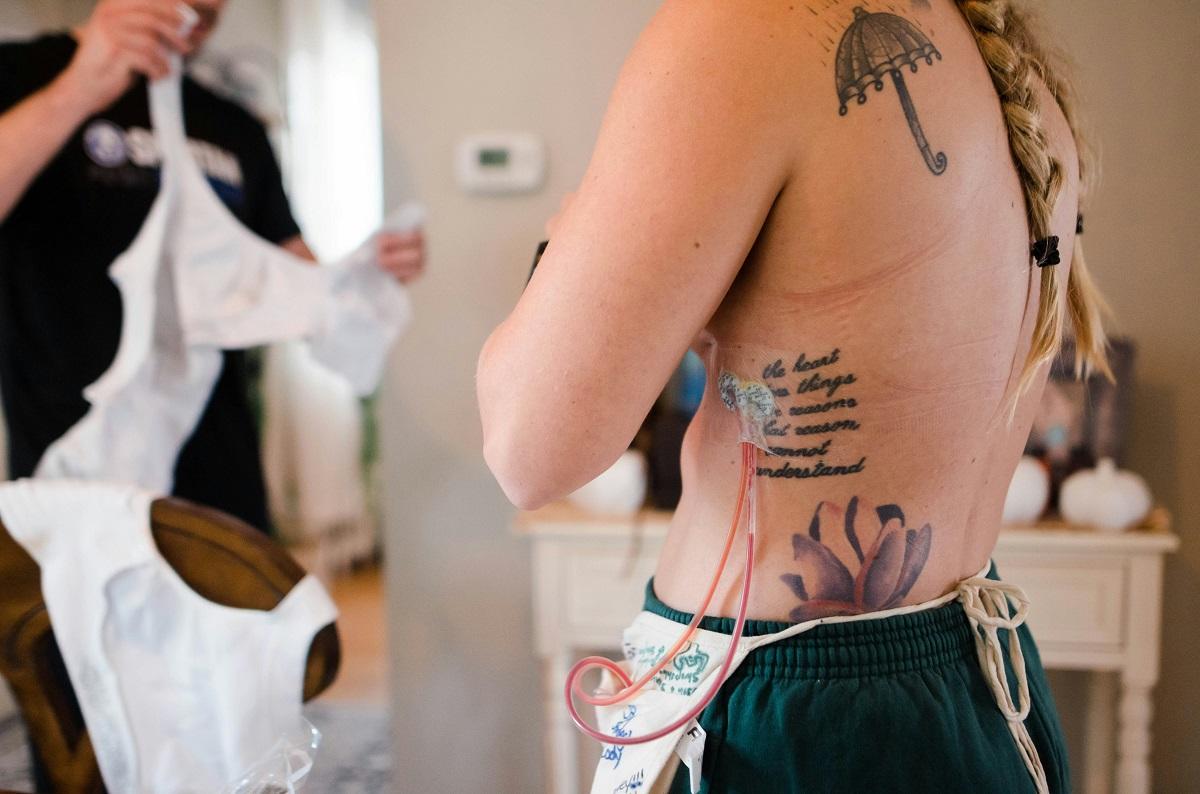 Tattooed woman post breast cancer surgery trying on bra