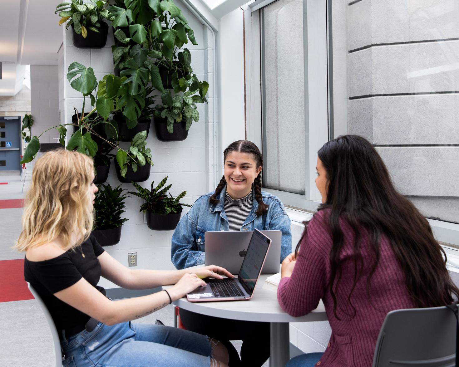 Three students sitting at a table laughing together,