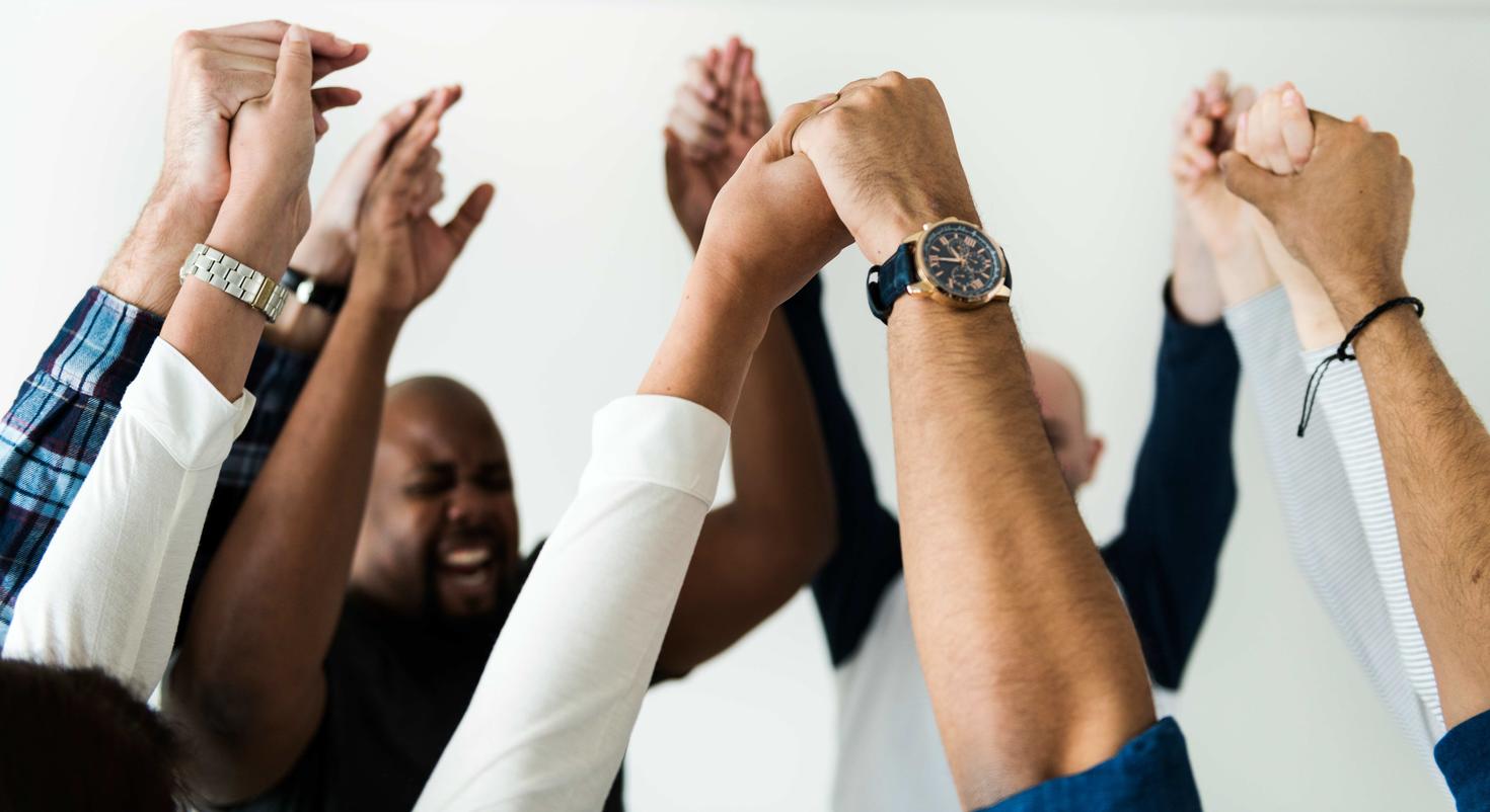 people holding raised hands in celebration