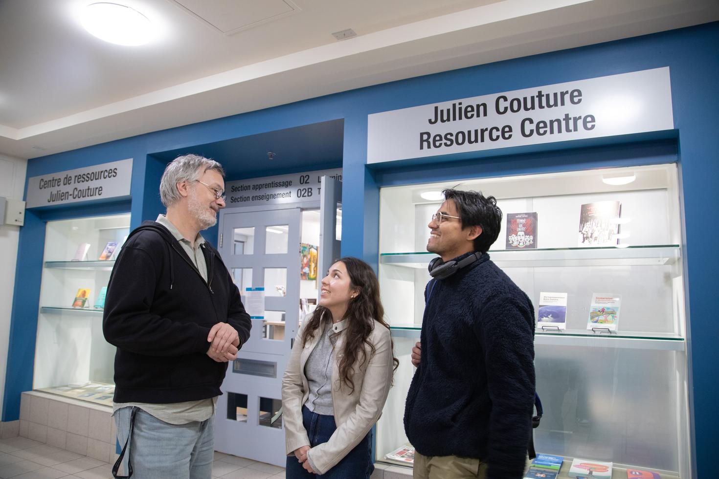 Three people talking to each other outside the Julien Couture Resource Centre.