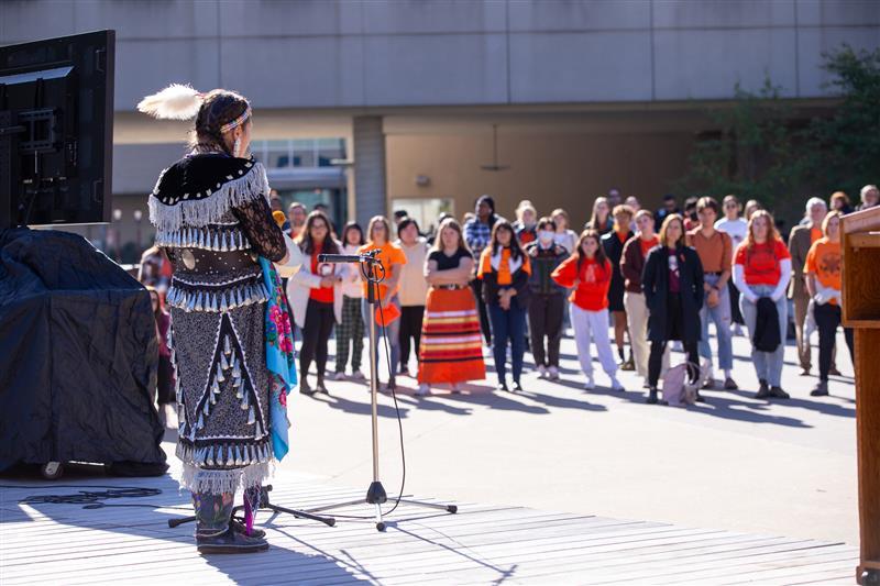 Claudette Commanda speaking at a Truth and Reconciliation event, addressing the audience with a microphone.