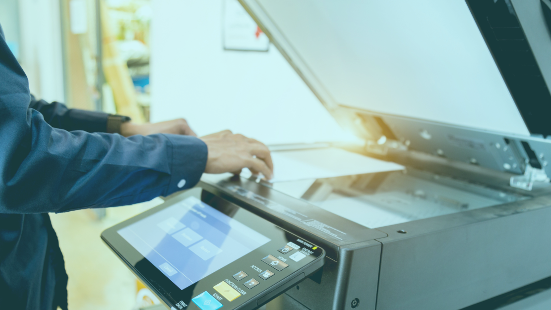 hands placing a paper in the scanning area of a printer 