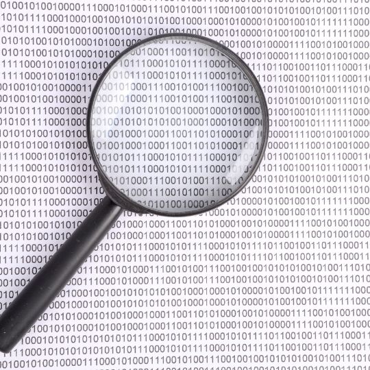 Magnifier upon a sheet of paper filled with zeros and ones