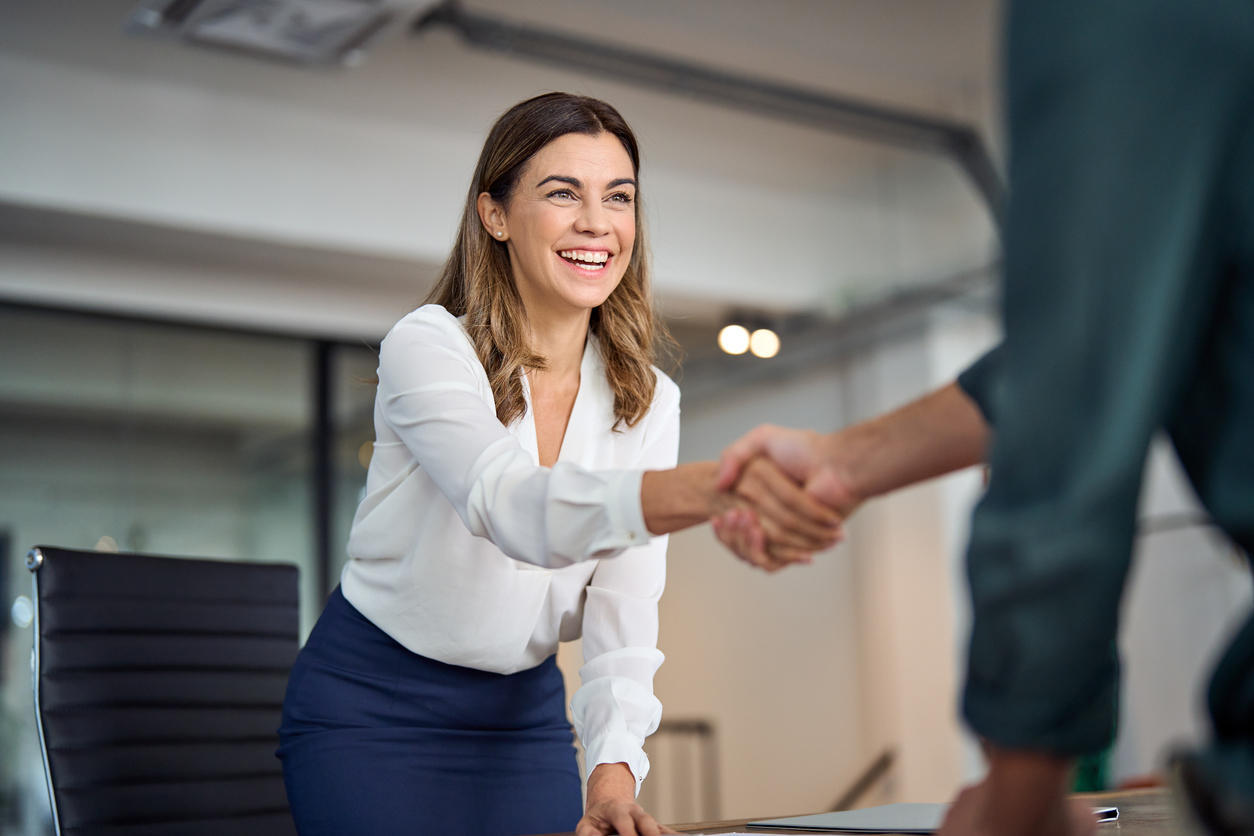 woman smiling and shaking hand with a another woman